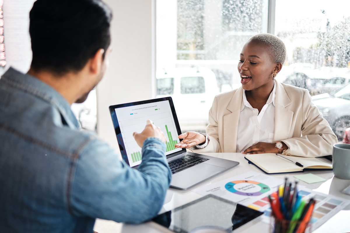 A man and woman review data on a laptop screen. | How DAM Reporting Can Transform Your Marketing